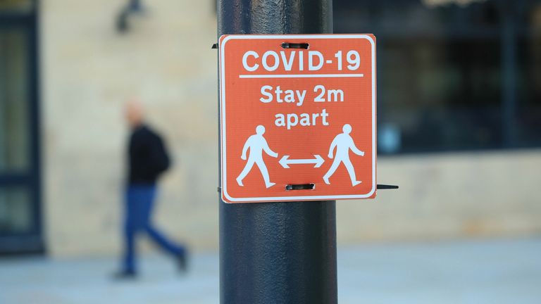 A sign advising people to stay six feet away on a lamppost in the center of Bradford, West Yorkshire