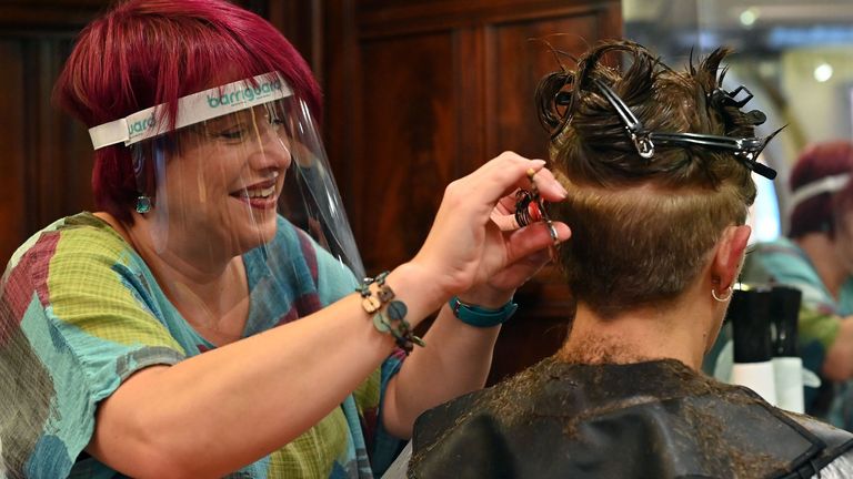 A hair stylist wears a PPE facemask as she works at a hair salon in Birkenhead, north west England on July 4, 2020. - Hairdressers can welcome back the public as part of a wider government plan to relaunch the hospitality, tourism and culture sectors and help the UK economy recover from more than three tough months of lockdown