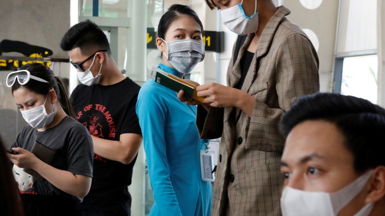 A Vietnam Airlines worker and passengers are seen wearing protective masks at Danang airport
