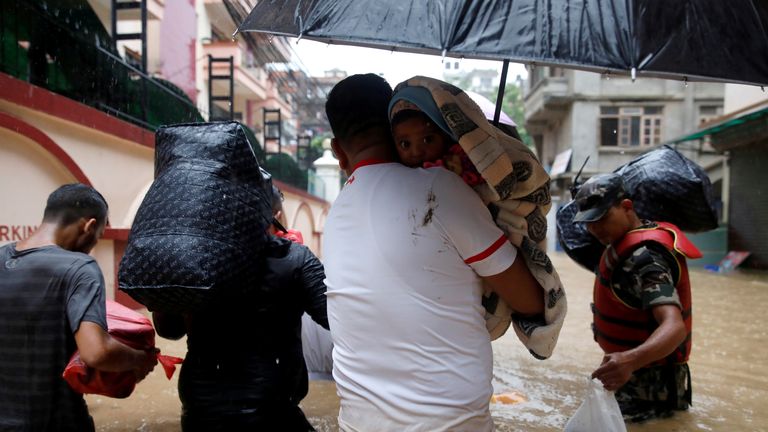 A man carrying a child walks towards the dry ground from a flooded colony in Kathmandu, Nepal July 12, 2019. REUTERS/Navesh Chitrakar