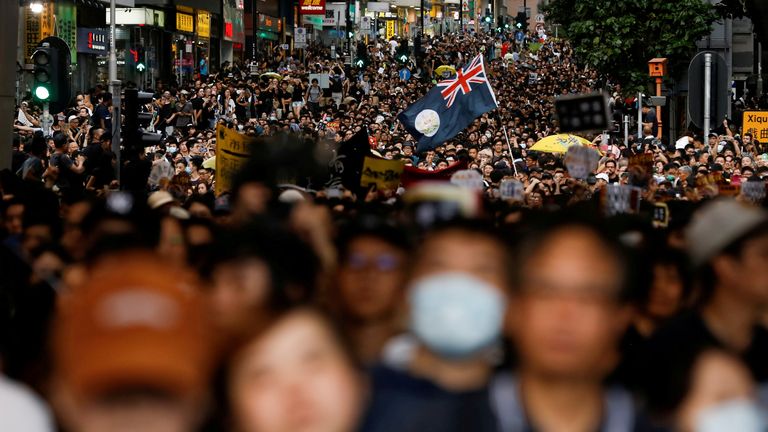 The colonial flag of Hong Kong is held aloft during a march by protesters
