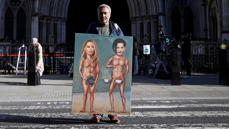 Artist Kaya Mar holds a painting of Depp and Heard outside the High Court