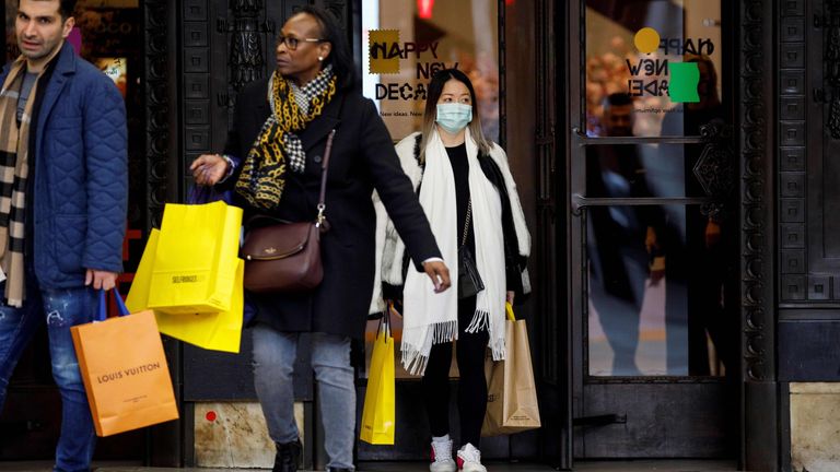 A mask-wearing shopper is seen leaving the Selfridges store in London