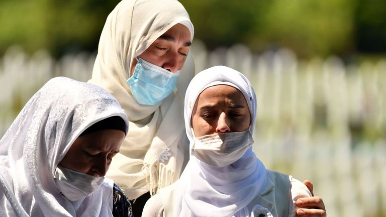 Bosnian Muslim women wearing face masks mourn in front of the casket of a newly identified victim