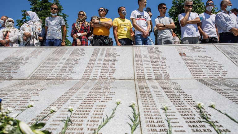 Mourners at the memorial look at the list of names of those who were killed