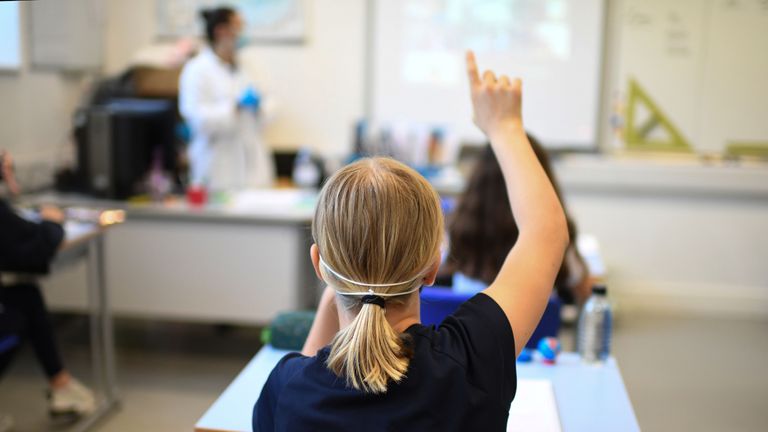 A Year 6 pupil wearing a face mask raises a hand to ask a question in a classroom at the College Francais Bilingue De Londres French-English bilingual school in north London on June 2, 2020 as schools in England partially reopen from coronavirus shutdown. - Schools partially reopened in England on June 2 and the most vulnerable were allowed to venture outdoors, despite warnings that the world's second worst-hit country was moving too quickly out of its coronavirus lockdown. (Photo by DANIEL LEAL-OLIVAS / AFP) (Photo by DANIEL LEAL-OLIVAS/AFP via Getty Images)