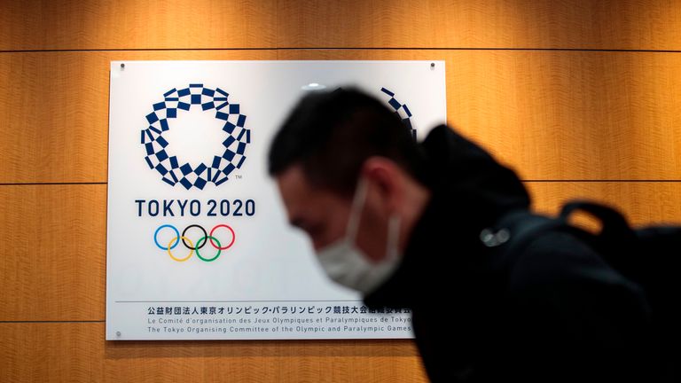 A reporter walks past a logo of the Tokyo 2020 Olympic Games after a press conference at the Tokyo 2020 headquarters in Tokyo on March 30, 2020. - The postponed Tokyo 2020 Olympics will open on July 23, 2021, organisers said on March 30, announcing the new date after the Games were delayed because of the coronavirus pandemic. The decision comes less than a week after organisers were forced to delay the Games under heavy pressure from athletes and sports federations as the global outbreak took hold. (Photo by Behrouz MEHRI / AFP) (Photo by BEHROUZ MEHRI/AFP via Getty Images)