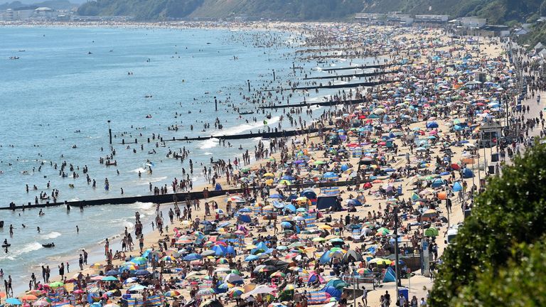 TOPSHOT - Beachgoers enjoy the sunshine as they sunbathe and play in the sea on Bournemouth beach in Bournemouth, southern England, on June 25, 2020. - Just days after lockdown ended and European travel restrictions were lifted, many were staying home in the cool as a heatwave hit the continent with temperatures touching 40 degrees Celcius. Britain was bracing for a flood of visitors to its beaches with the heatwave expected to last until Friday and temperatures set to climb into the mid-30s in the south and centre of the country. (Photo by Glyn KIRK / AFP) (Photo by GLYN KIRK/AFP via Getty Images)