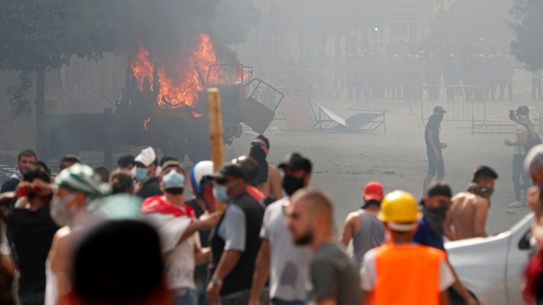 A vehicle burns as demonstrators try to break through a barrier near the parliament building