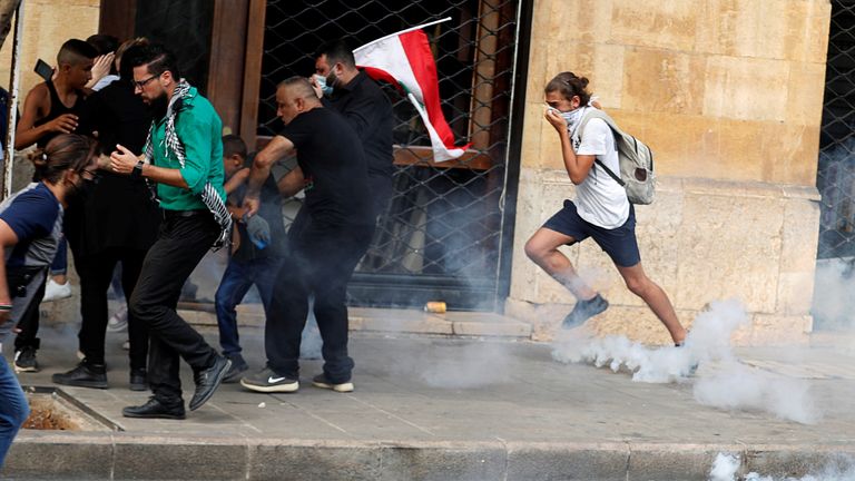 Demonstrators run away from tear gas fired by riot police