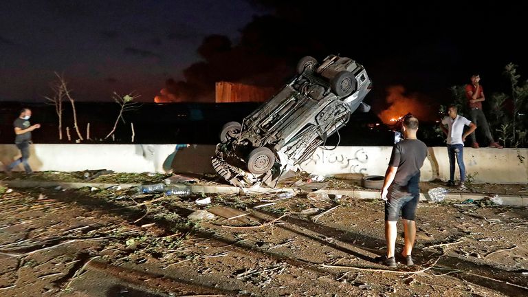 People gather by cars destroyed following an explosion at the port of Beirut