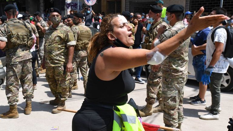 An injured woman protested against the government as Emmanuel Macron visited one of the worst-hit neighbourhoods