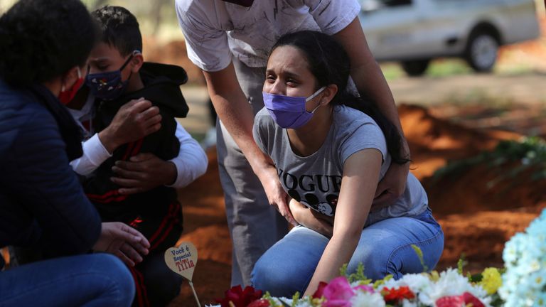 A woman mourns her mother, who died from suspected coronavirus, at a funeral in Sao Paulo