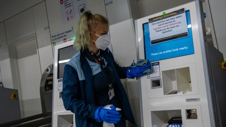 A cleaner is seen wiping down a machine at Gatwick Airport during the pandemic