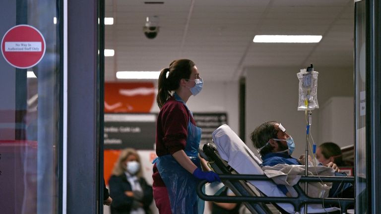 A medical professional in PPE, including gloves, an apron and a face mask as a precautionary measure against Covid-19, pushes a patient, also waering a facemask, as he lays on a bed, inside St Thomas' Hospital in north London, on April 1, 2020, as life in Britain continues during the nationwide lockdown to combat the novel coronavirus pandemic. - Britain reported 563 daily coronavirus deaths on Wednesday, the first time the national toll has exceeded 500, bringing the total fatalities to 2,352, 