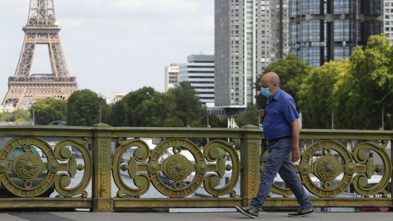 A man wears a protective face mask while walking across Pont Mirabeau bridge, near the Eiffel Tower, on August 27, 2020, in Paris. - France's prime minister on August 27 announced face masks will become compulsory throughout Paris, expressing concern over an "undeniable" trend of expanding coronavirus infection in the country. (Photo by Ludovic MARIN / AFP) (Photo by LUDOVIC MARIN/AFP via Getty 