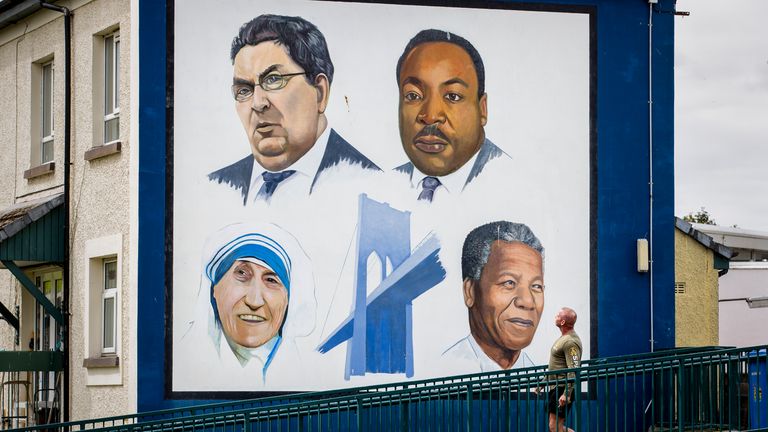 A man walks past the Bogside mural in Derry City of John Hume, Martin Luther King Jr, Mother Teresa, and Nelson Mandela.