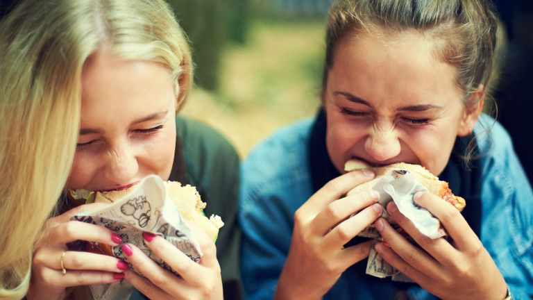 Shot of two young women eating at an outdoor festival