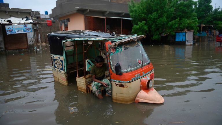 A boy sits in a auto-rickshaw in a flooded area after heavy monsoon rains in Pakistan's port city of Karachi 