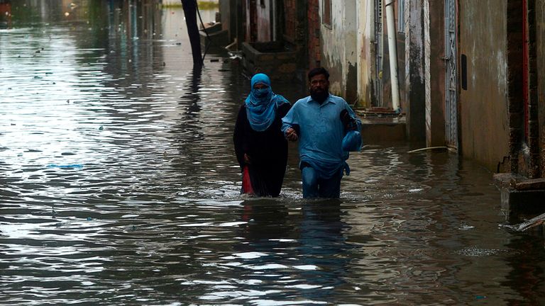 Residents wade through the flooded streets of Karachi