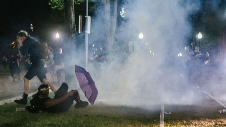 Demonstrators retreat from tear gas fired by police