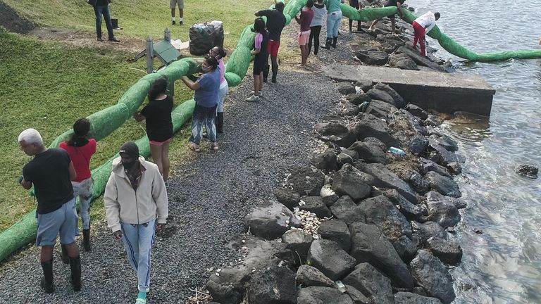 Volunteers carrying a handmade oil barrier to block leaked oil