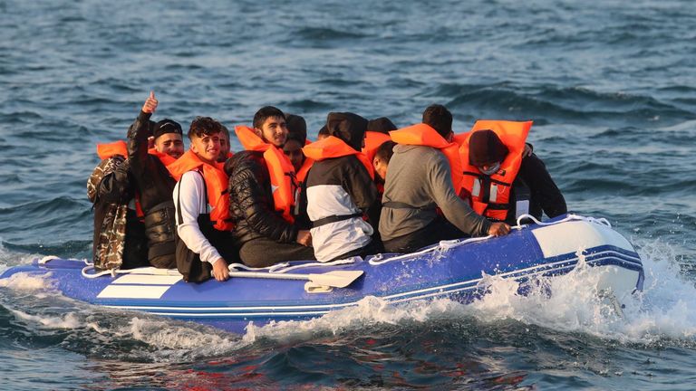 A man gives a thumbs up as he sits with a group of people, thought to be migrants, crossing the Channel in a small boat