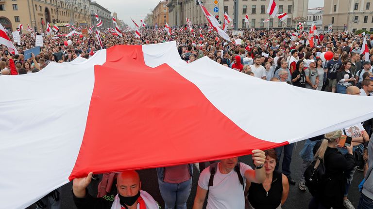 People carry a large historical flag of Belarus during an opposition demonstration