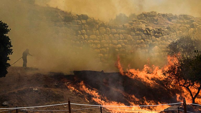 A firefighter works to put out a wildfire near the archaeological site of Mycenae 