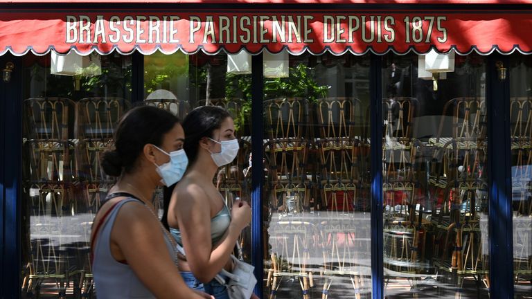 Women wearing a protective face mask pass in front a closed a restaurant in Paris on May 30, 2020, as France eases lockdown measures taken to curb the spread of the COVID-19 (the novel coronavirus)