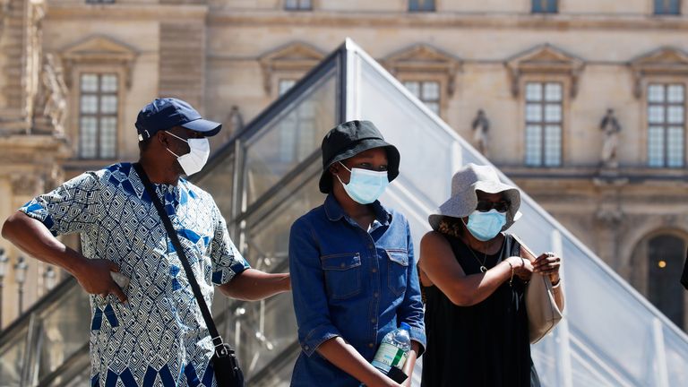 People wearing protective masks walks near the Louvre Museum