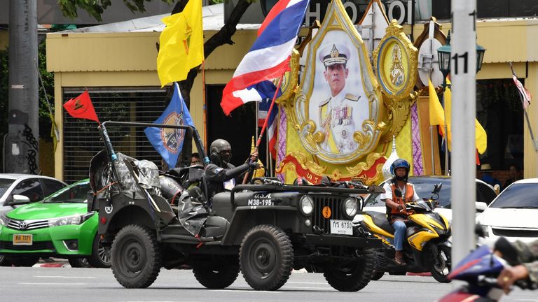 A royalist protester waves a Thai national flag while driving past a rally in Bangkok on August 16, 2020, ahead of anti-government protests in the Thai capital. - Some 50 royalist protesters gathered on August 16 at Democracy Monument, the same venue where anti-government protesters are set to rally in Bangkok against the government of Premier Prayut-O-Cha as tensions rise in the kingdom after the arrest of three activists leading the pro-democracy movement. (Photo by Mladen ANTONOV / AFP) (Phot