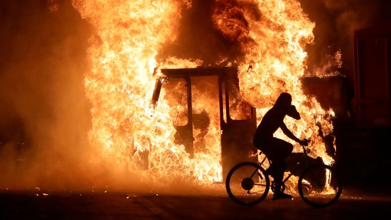 A man on a bike rides past a city truck on fire outside the Kenosha County Courthouse in Kenosha, Wisconsin, U.S., during protests following the police shooting of Black man Jacob Blake August 23, 2020. Picture taken August 23, 2020. Mike De Sisti/Milwaukee Journal Sentinel via USA TODAY via REUTERS MANDATORY CREDIT
