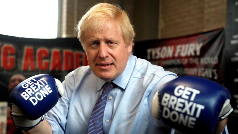 Britain's Prime Minister and leader of the Conservative Party, Boris Johnson wears boxing gloves emblazoned with "Get Brexit Done" as he poses for a photograph at Jimmy Egan's Boxing Academy in Manchester north-west England on November 19, 2019, during a general election campaign trip. - Britain will go to the polls on December 12, 2019 to vote in a pre-Christmas general election. (Photo by Frank Augstein / POOL / AFP) (Photo by FRANK AUGSTEIN/POOL/AFP via Getty Images)