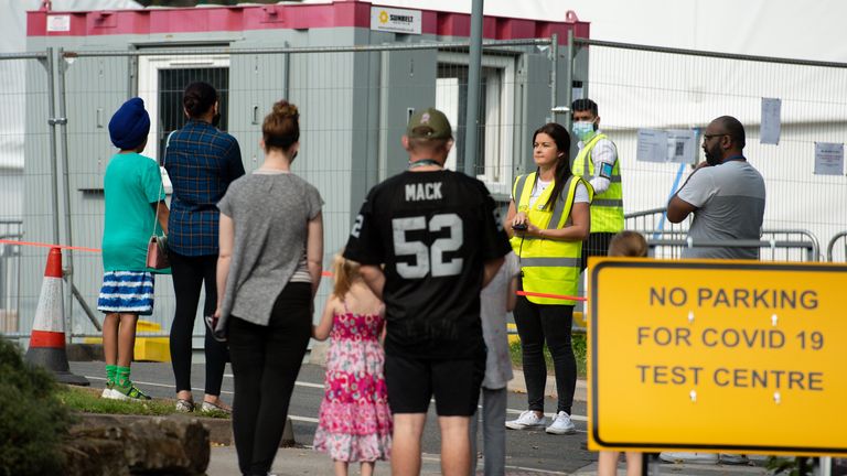 Members of the public speak with staff whilst queuing at a coronavirus testing facility at the University of Birmingham.