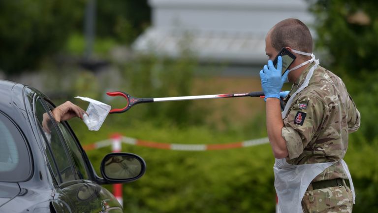 A person passes a completed coronavirus self test package through a car window to a reservist from the Royal Anglian Regiment at Harlow Football Club, Harlow, following the introduction of measures to bring England out of lockdown.