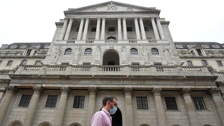 A worker wearing a protective face mask walks past the Bank of England in the City of London, Britain, August 6, 2020.