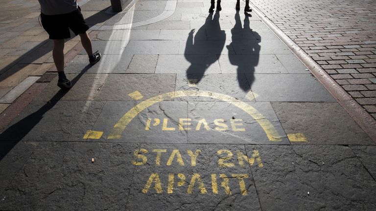 The changing face of the high street. People cast shadows walking past a social distancing information sign painted on the pavement on the high street in Dundee in Scotland, some six months on from the evening of March 23 when Prime Minister Boris Johnson announced nationwide restrictions.