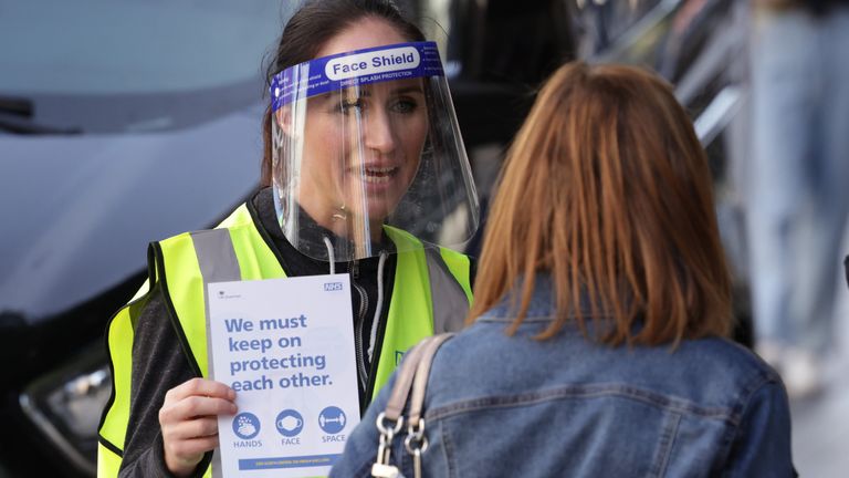 A woman handing out leaflets promoting the new NHS Covid-19 app in Liverpool.