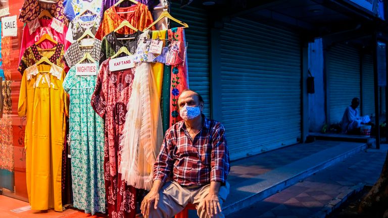 A man waits for customers at his clothing store in New Delhi 