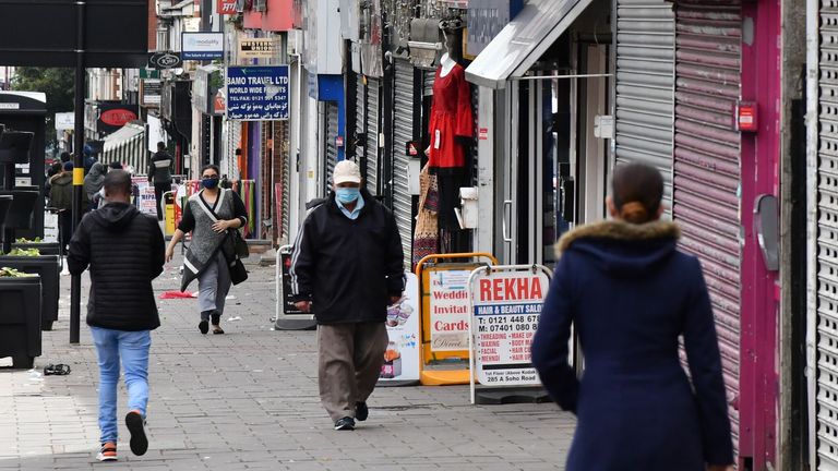 Pedestrians wearing protective face masks walk past shops in the Handsworth area of Birmingham, central England on August 22, 2020, as Britain&#39;s second-city, home to more than one million people, was made an "area of enhanced support", because of concern about a spike in cases of the novel coronavirus. (Photo by JUSTIN TALLIS / AFP) (Photo by JUSTIN TALLIS/AFP via Getty Images)