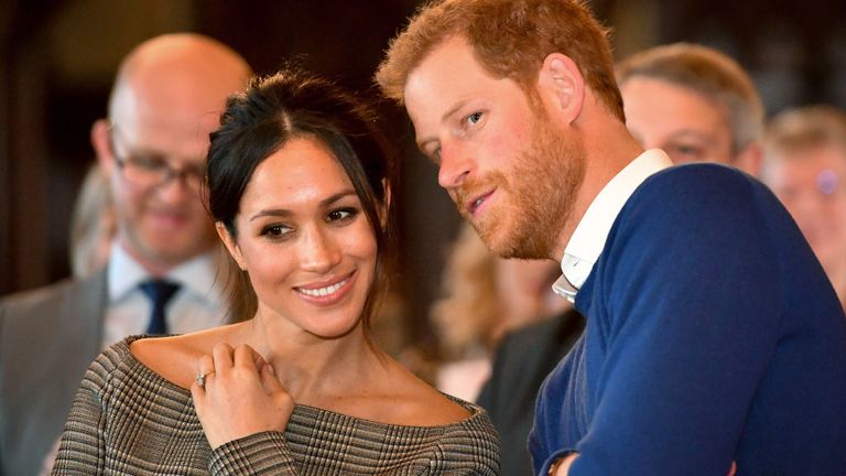 Prince Harry whispers to Meghan Markle as they watch a dance performance by Jukebox Collective in the banqueting hall during a visit to Cardiff Castle in 2018