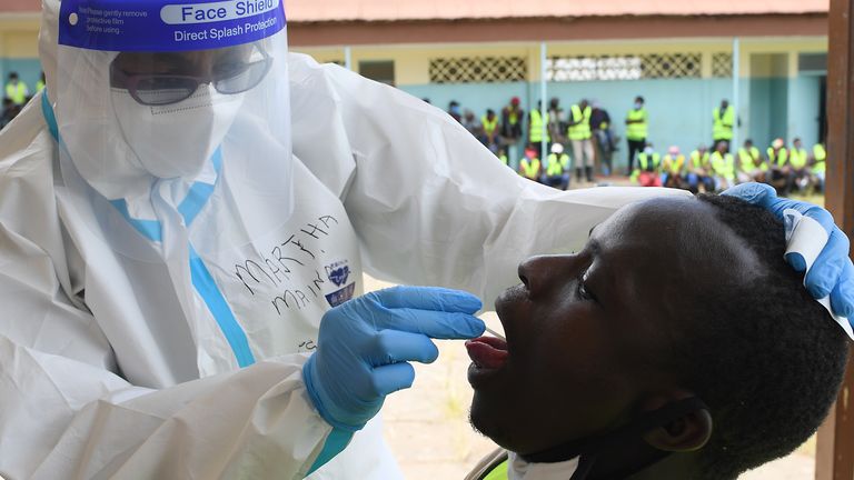 A Kenyan health worker takes an oral swab from a resident of Eatstleigh, during a mass testing exercise for the COVID-19 coronavirus in Nairobi on May 20, 2020