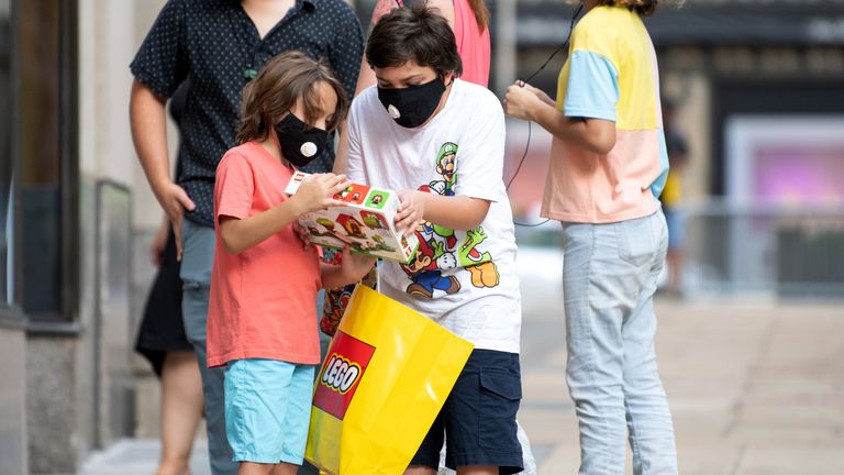 Children wearing masks look at a Lego box outside the Lego store at Rockefeller Center as the city continues Phase 4 of re-opening following restrictions imposed to slow the spread of coronavirus on August 02, 2020 in New York City. 