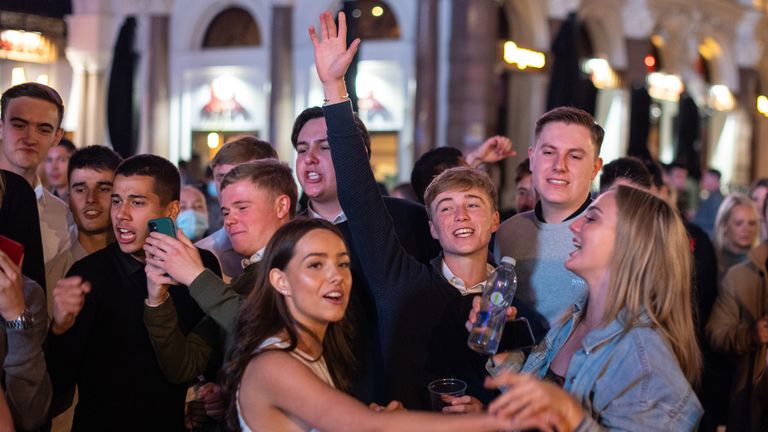 People sing and dance as they watch a street performer in Leicester Square