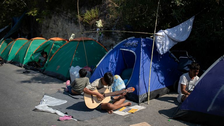 A boy plays the guitar at the area where refugees and migrants from the destroyed Moria camp are sheltered, near a new temporary camp, on the island of Lesbos, Greece, September 16, 2020. REUTERS/Alkis Konstantinidis