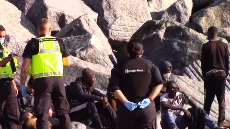 Migrants sur la plage avec des agents des forces frontalières.