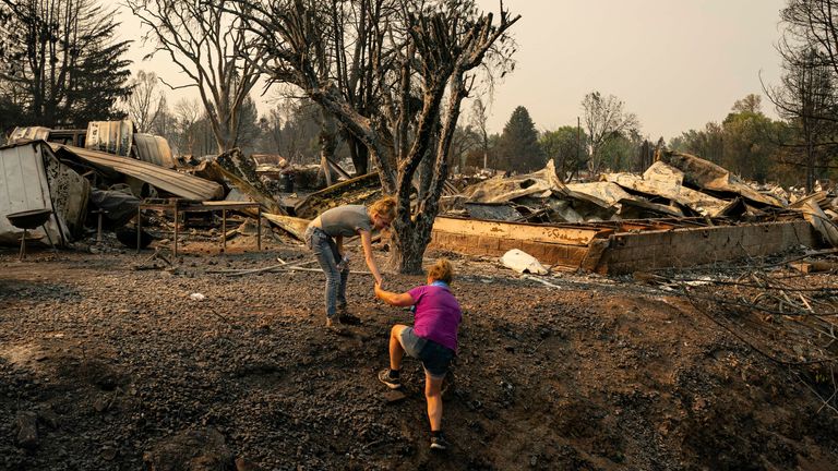 PHOENIX, OR - SEPTEMBER 10: Amie Emery (R) and her daughter, Erin Emery, make their way to her mother-in-laws destroyed home, which was located in a mobile home park overcome by fire, on September 10, 2020 in Phoenix, Oregon. Hundreds of homes in the town have been lost due to wildfire. (Photo by David Ryder/Getty Images)