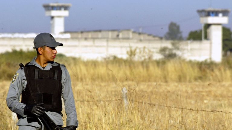 A Mexican Federal Police officer guards the access road to Puente Grande federal prison near Guadalajara w