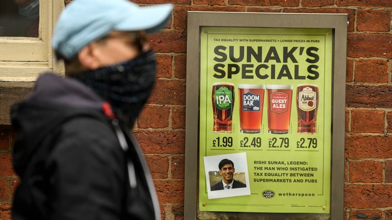 A man walks past a pub advertising &#39;Sunak&#39;s Specials&#39; promotion on beer, referencing the Chancellor of the Exchequer Rishi Sunak in Manchester on August 30, 2020 